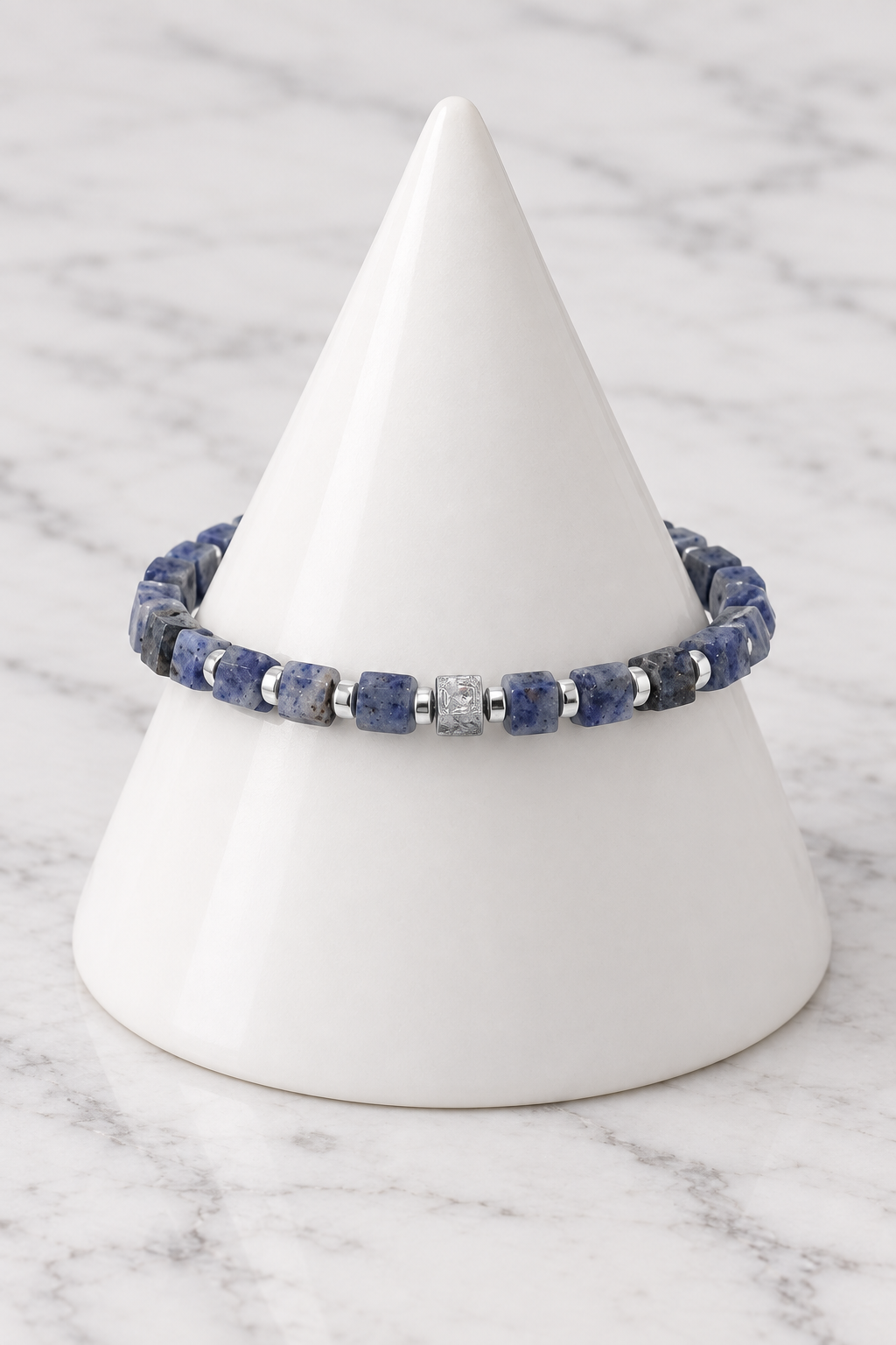 Blue cube bead bracelet on white porcelain cone, marble background