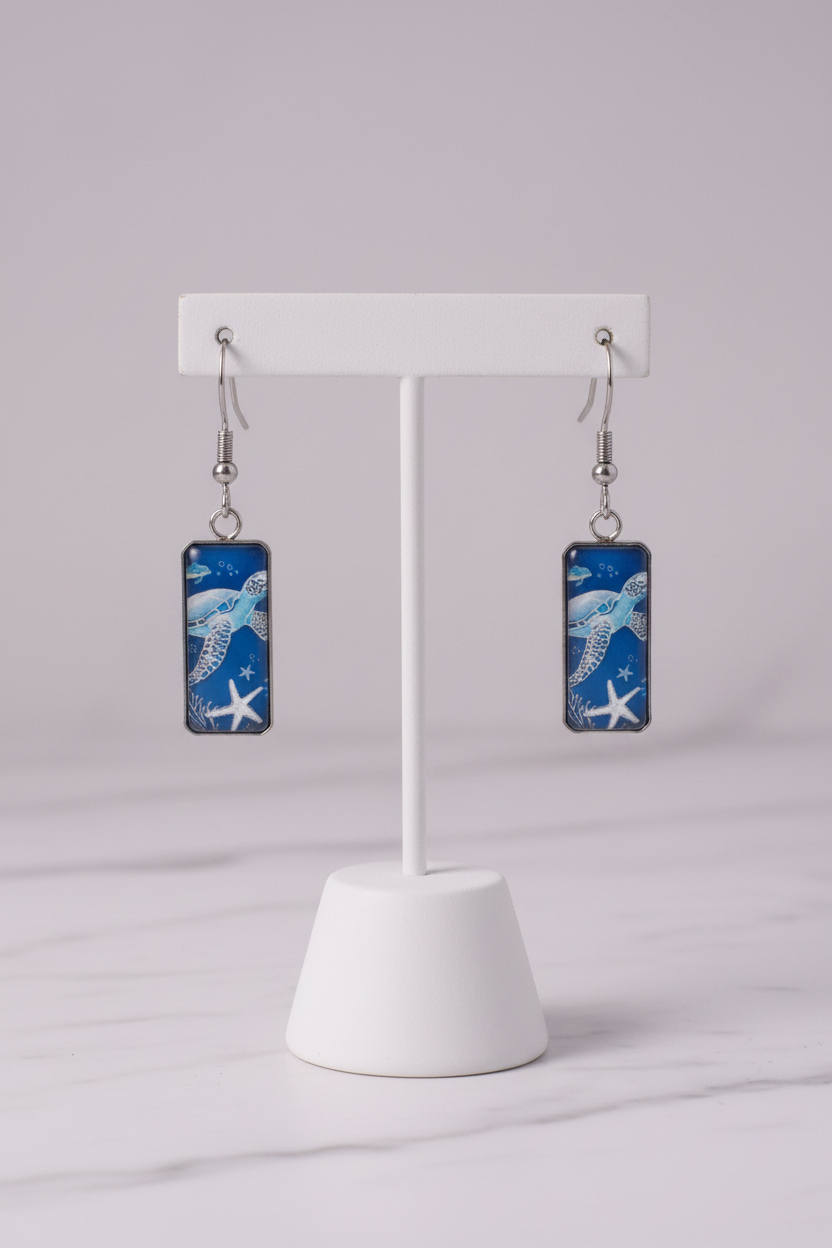 Blue sea turtle earrings on white porcelain stand