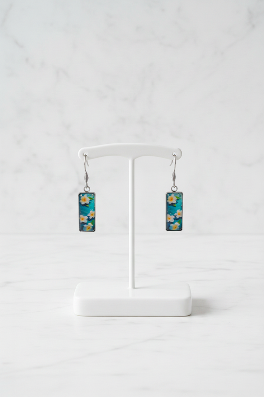 Corrected frangipani earring pair on white porcelain stand