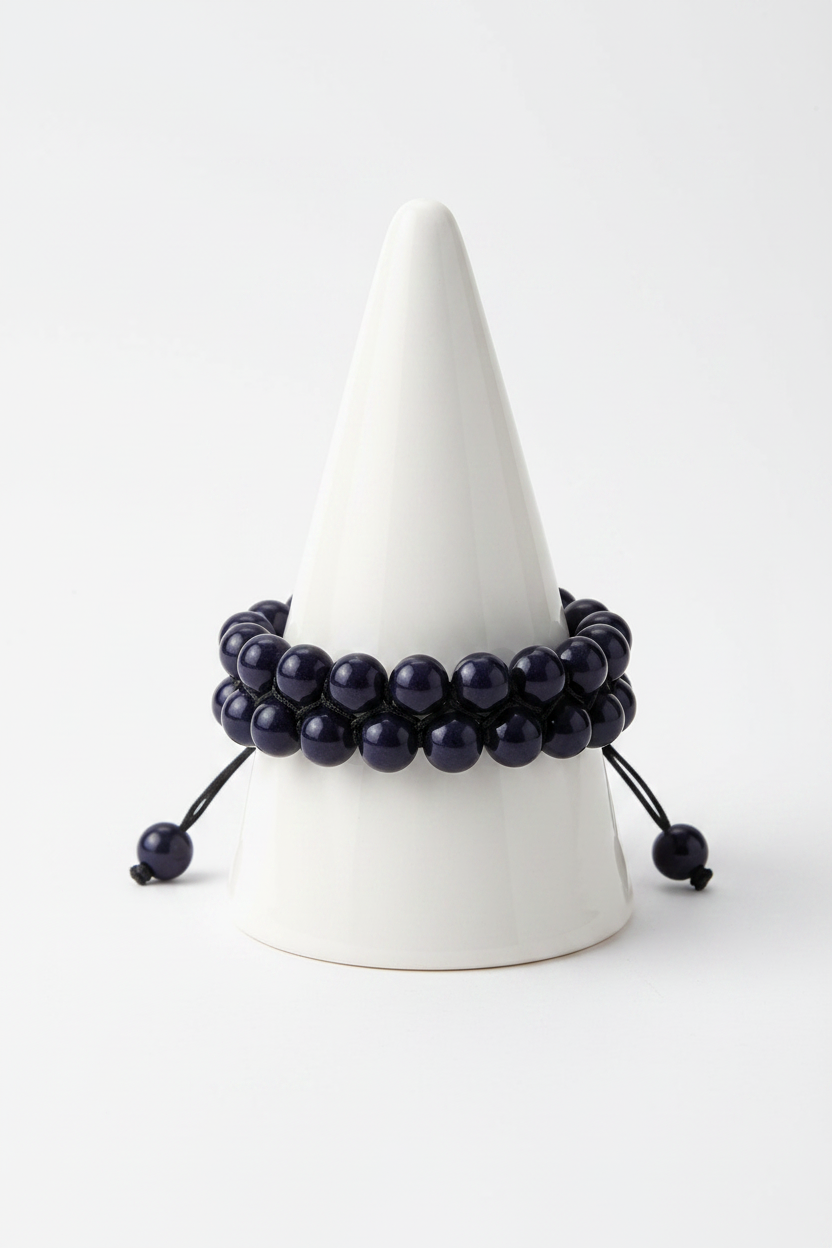 Double strand black onyx bracelet on white porcelain cone stand