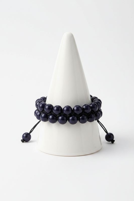 Double strand black onyx bracelet on white porcelain cone stand