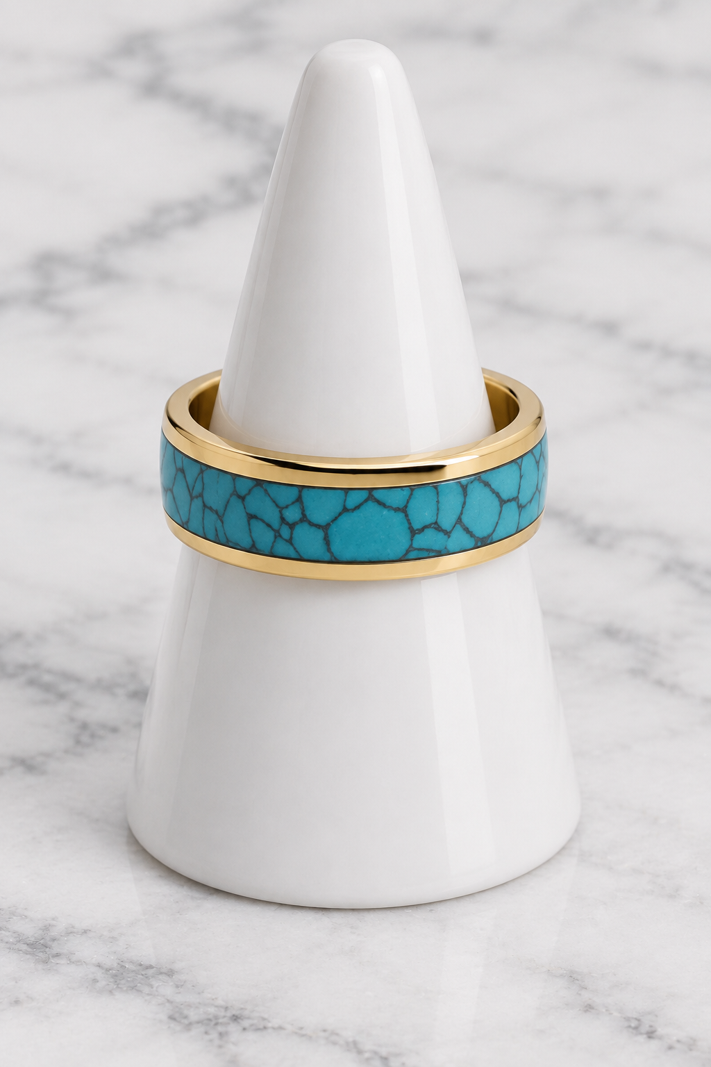 Gold turquoise inlay ring on white porcelain cone, marble background