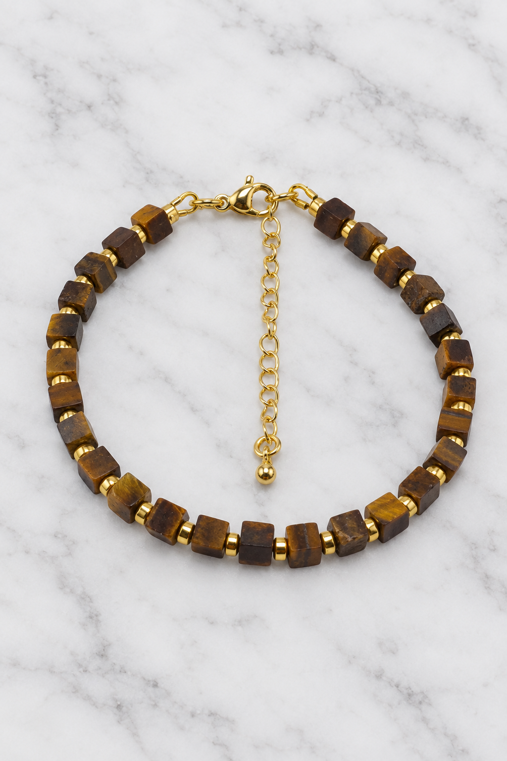 Golden-brown cube bead bracelet with gold spacers flat lay on white marble