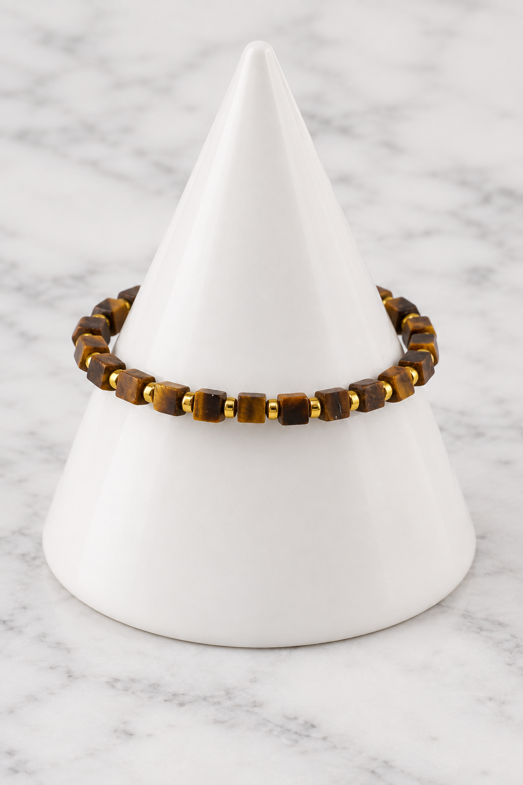 Golden-brown cube bead bracelet with gold spacers on white porcelain cone
