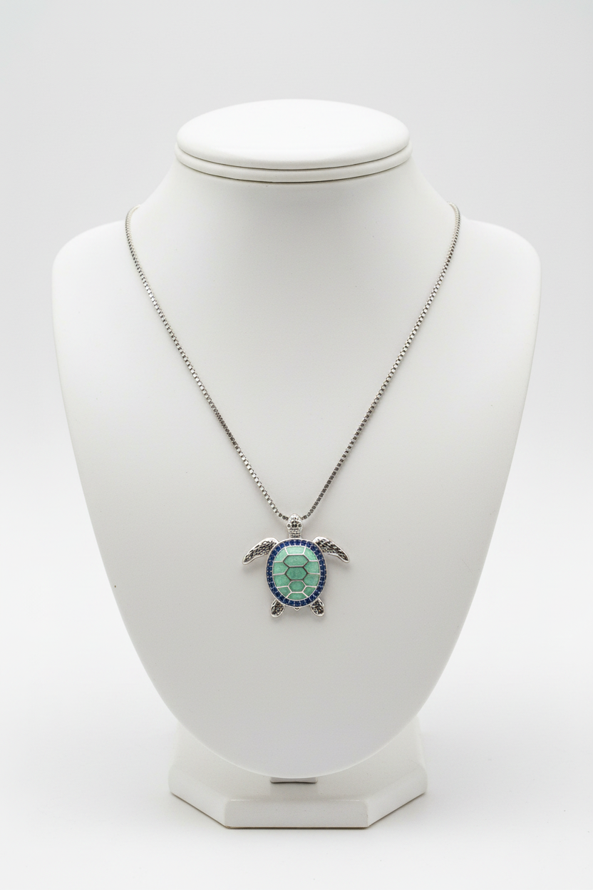 Green turtle necklace on white porcelain bust stand