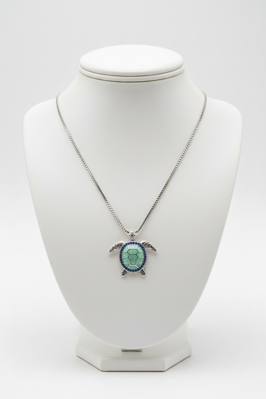 Green turtle necklace on white porcelain bust stand