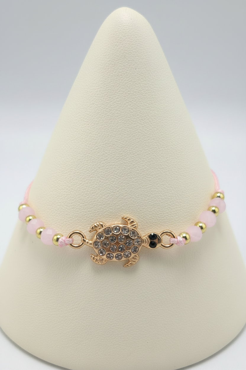Pink turtle bracelet on white porcelain cone stand