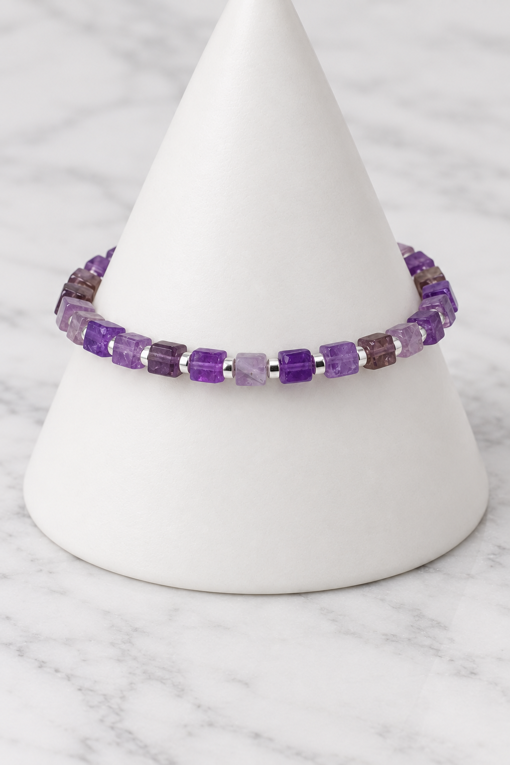 Purple cube bead bracelet with silver spacers on white porcelain cone