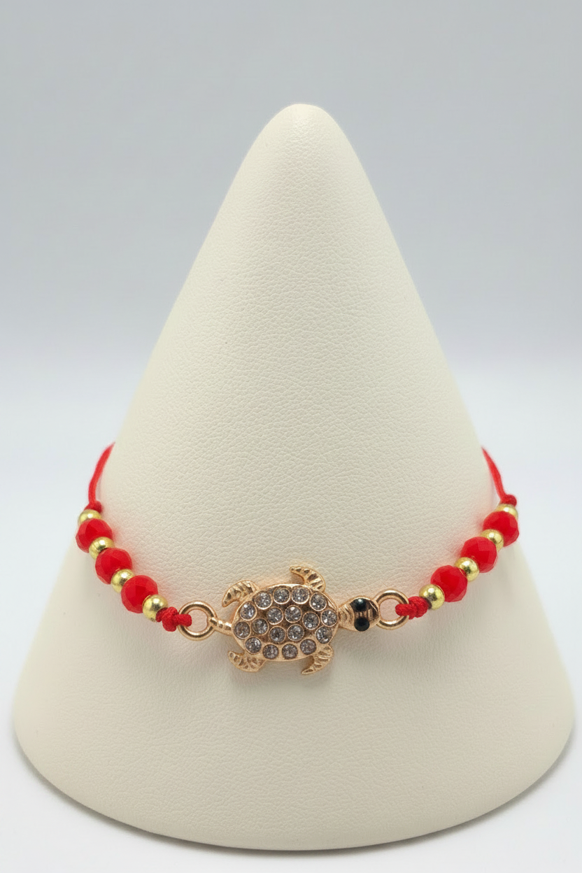 Red turtle bracelet on white porcelain cone stand