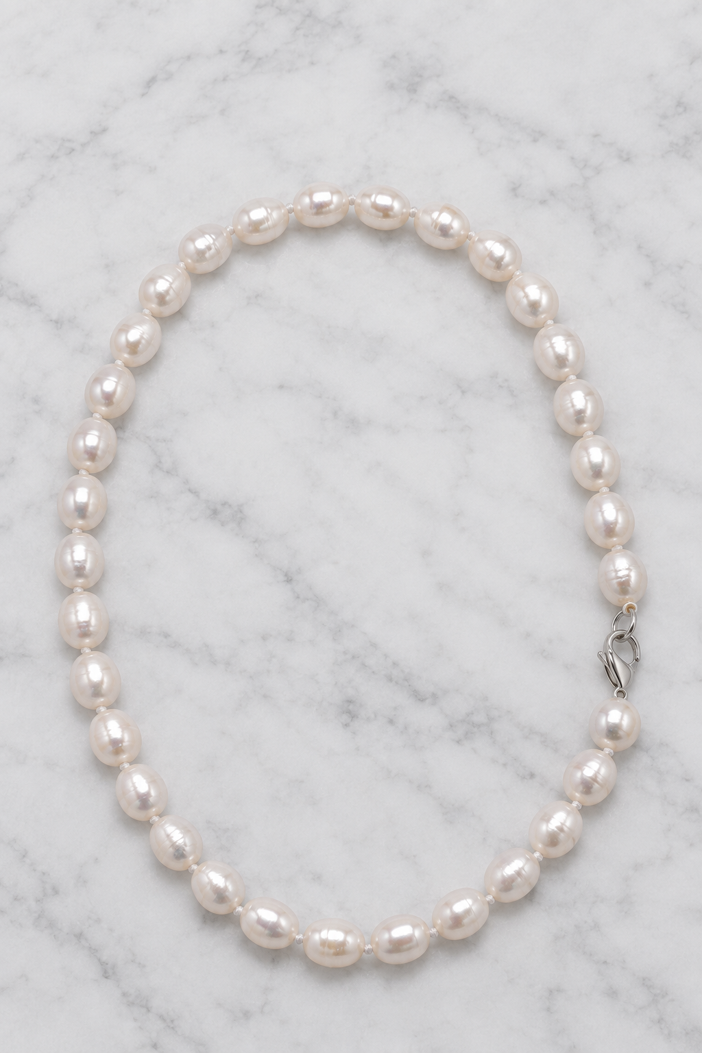 White pearl necklace flat lay on white marble