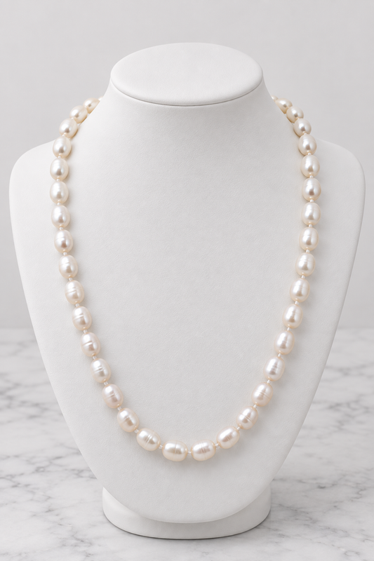 White pearl necklace on white porcelain bust, marble background